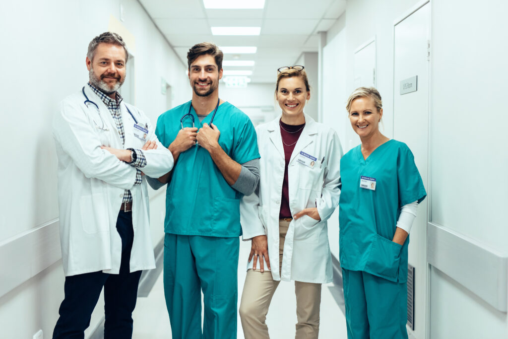 Portrait,Of,Positive,Medical,Professionals,Standing,In,Hallway,And,Looking